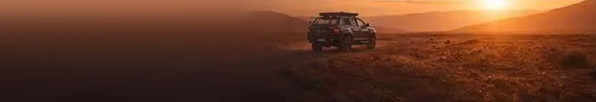 4x4 parked on a desert track at sunset
